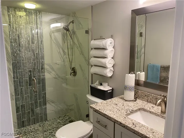 a bathroom with a granite countertop sink a toilet and shower