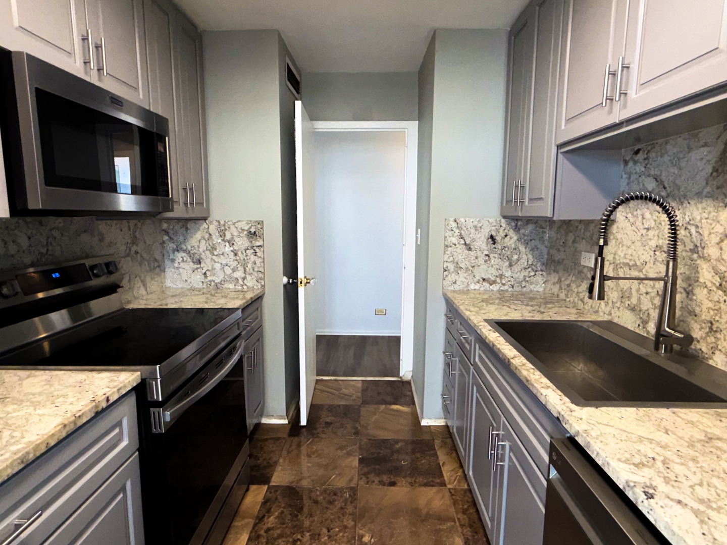 6301 North Sheridan Road, Unit 24E Chicago, IL 60660 - Photo 12 of 57 a kitchen with granite countertop stainless steel appliances a stove sink and microwave