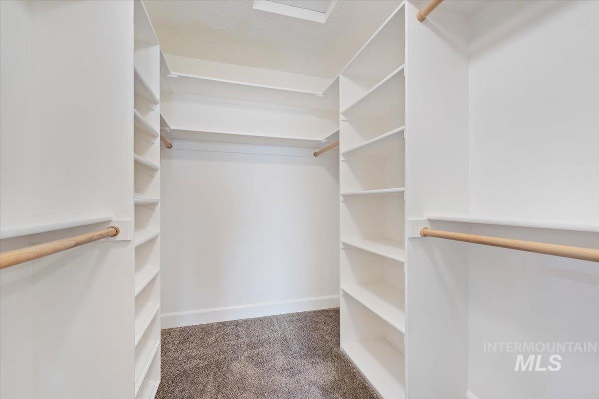 24240 Tiger Lane Caldwell, ID 83607 - Photo 23 of 50 Built-in closet system featuring white shelving, multiple hanging rods, and carpet flooring