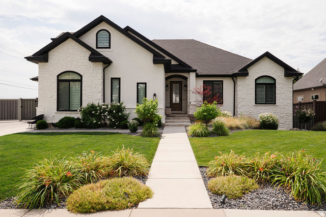 924 Country Lane Farmington, UT 84025 - Photo 3 of 91 Contemporary residence featuring a blend of white stucco and stone veneer, dark trim accents, a concrete walkway, and a meticulously landscaped front yard with varied plantings