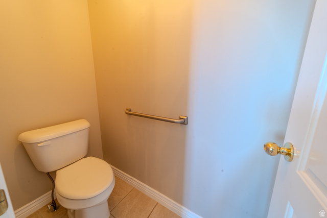 598 Hollow Creek Road Draper, UT 84020 - Photo 94 of 110 Neutral-toned walls complement the light-colored toilet and floor tiling, featuring a metal grab bar and a white door with a brass-finish knob