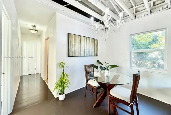 a view of a dining room with furniture a chandelier and a window