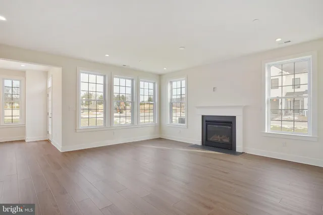 an empty room with wooden floor fireplace and windows
