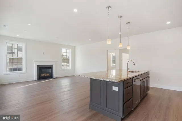 a kitchen with stainless steel appliances granite countertop a sink a stove and a wooden floor