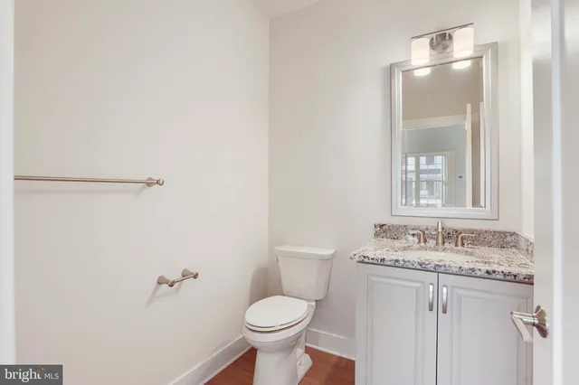 a bathroom with a granite countertop sink toilet and mirror