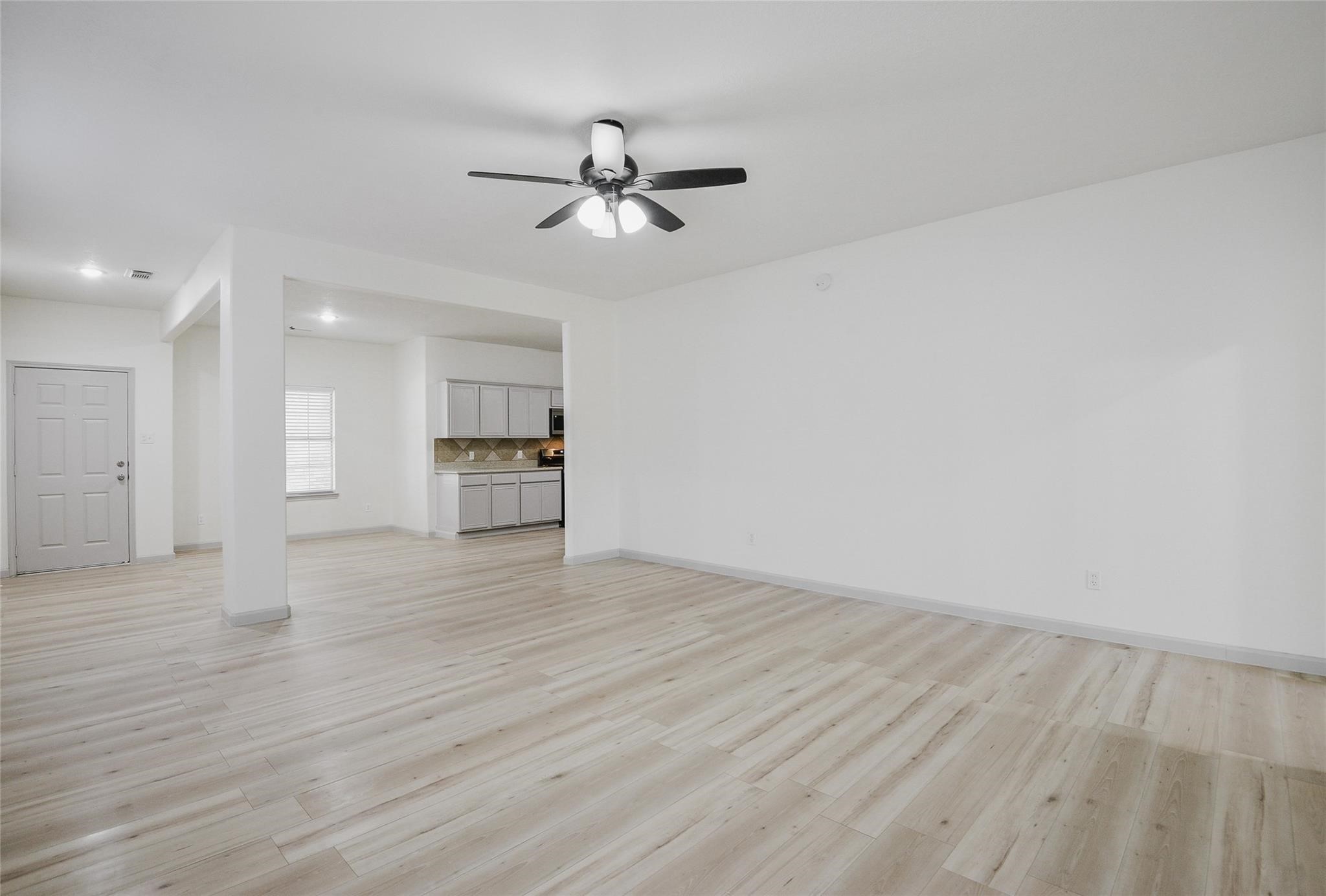 6627 Stonecross Creek Lane Katy, TX 77449 - Photo 17 of 30 a view of an empty room with wooden floor and a kitchen