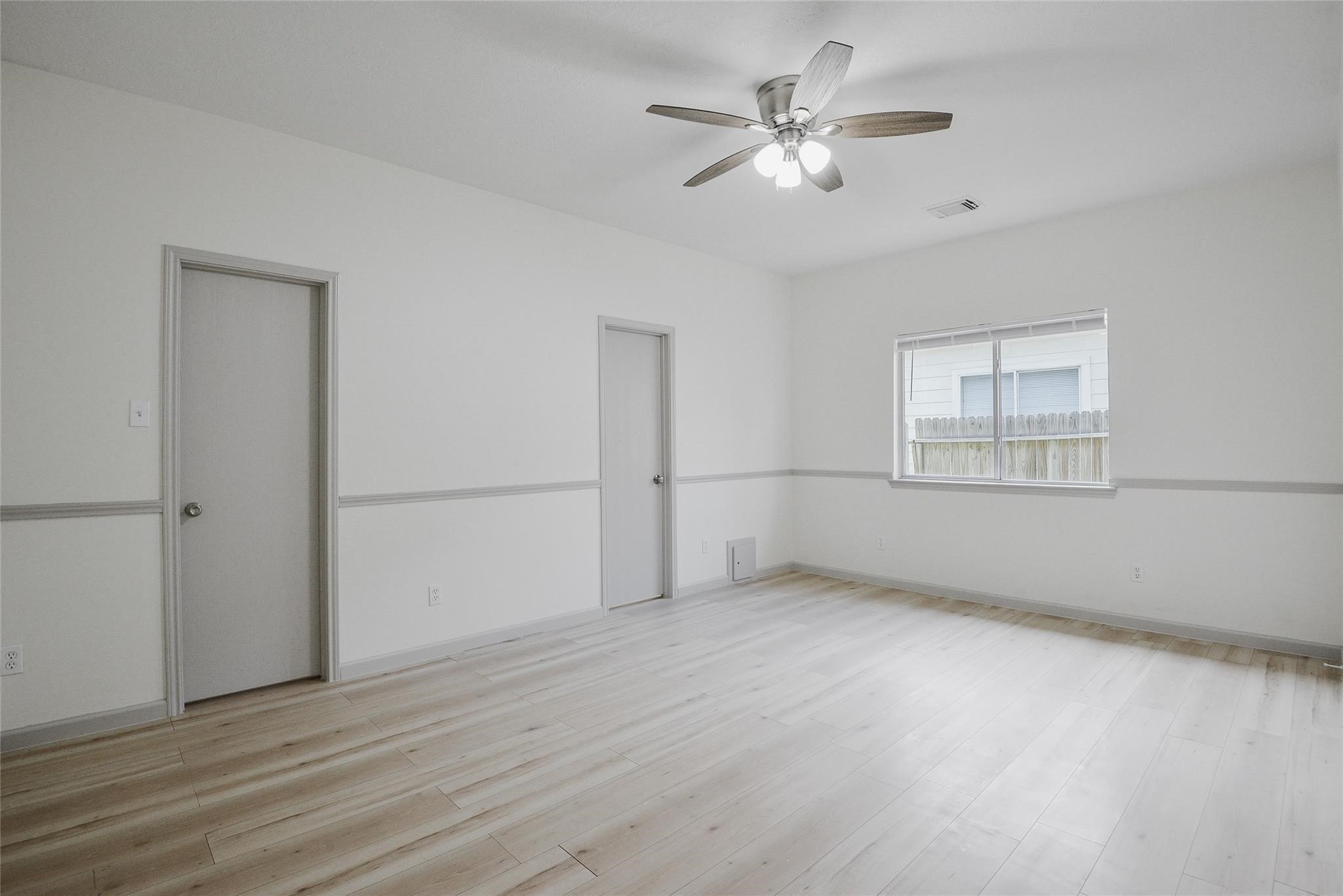 6627 Stonecross Creek Lane Katy, TX 77449 - Photo 18 of 30 an empty room with wooden floor chandelier fan and windows