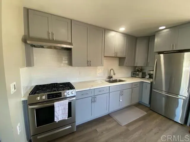 a kitchen with stainless steel appliances granite countertop a stove a refrigerator and a sink