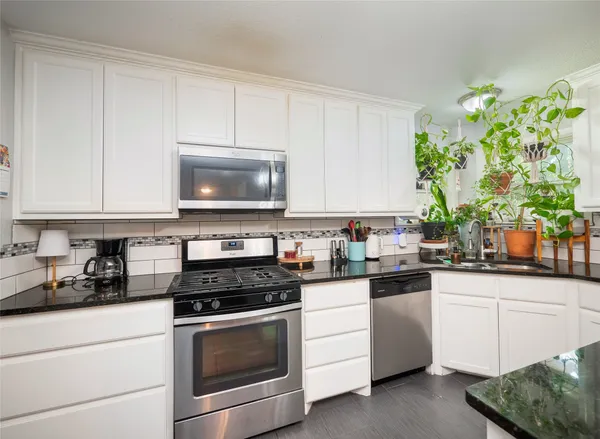 a kitchen with white cabinets and appliances