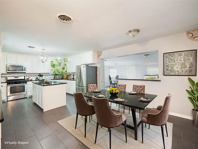 a kitchen with a dining table chairs and refrigerator