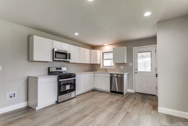 a kitchen with a sink wooden floor and stainless steel appliances