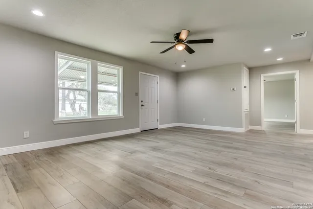 a view of an empty room with window and wooden floor
