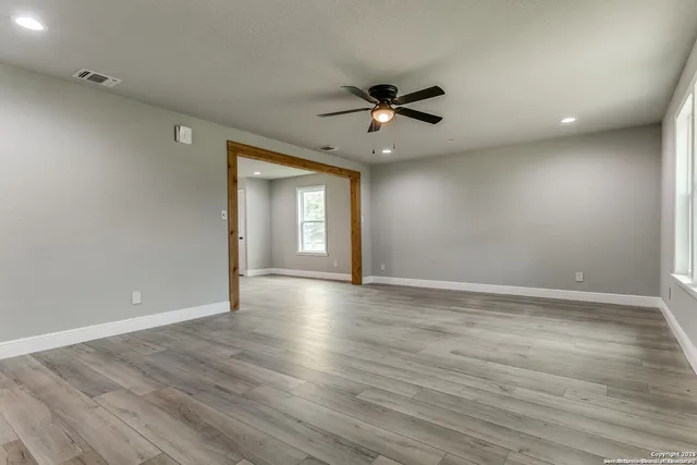 a view of empty room with wooden floor and fan