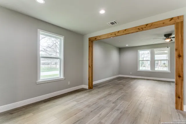 an empty room with wooden floor and windows