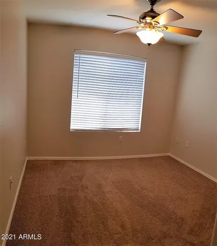 an empty room with windows and fan