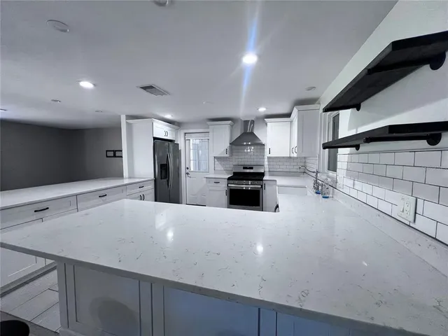 a large kitchen with stainless steel appliances a sink a stove and cabinets