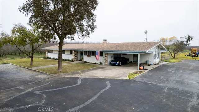 a view of a white house with a large space and a car parked in front of it