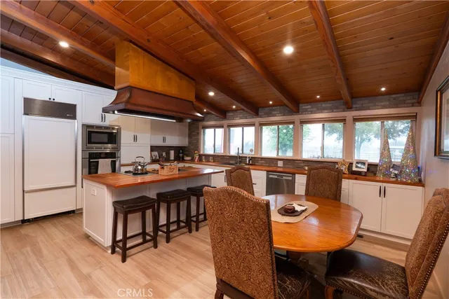 a dining hall with stainless steel appliances kitchen island granite countertop a table chairs and a refrigerator