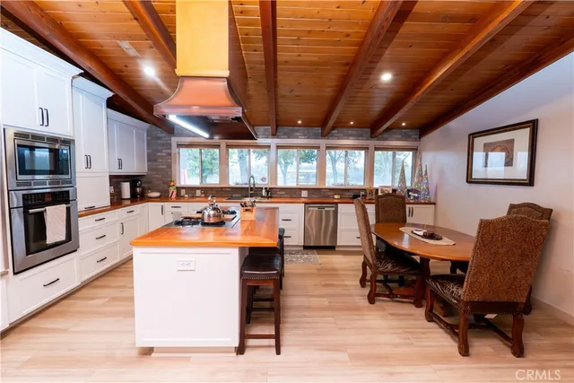 a large white kitchen with a stove a sink a refrigerator and cabinets