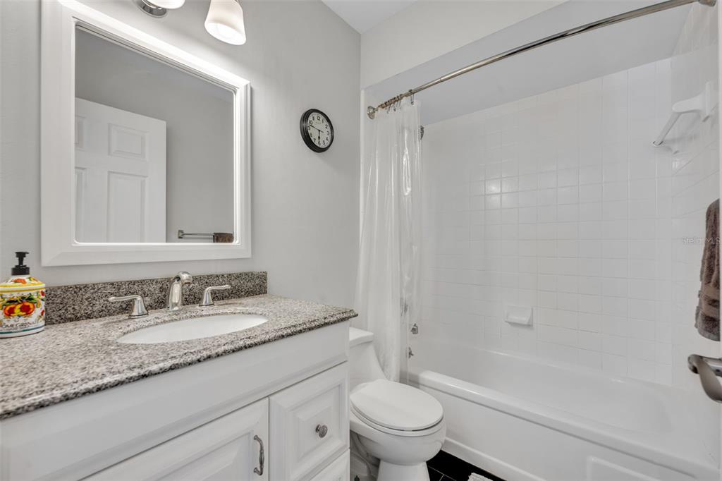 5377 Vineland Road, Unit 1D Orlando, FL 32811 - Photo 17 of 25 a bathroom with a granite countertop sink a toilet and a bathtub