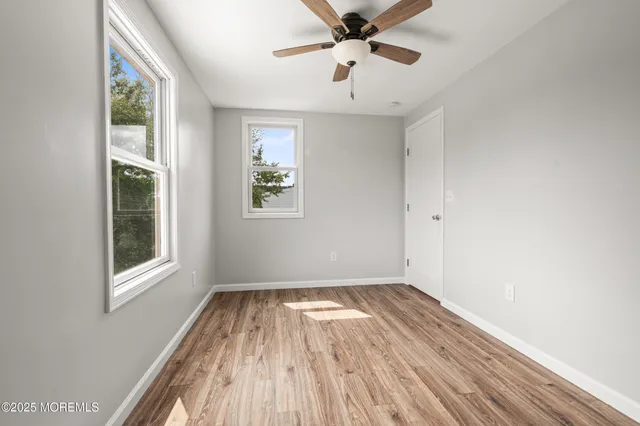 a view of empty room with wooden floor and fan