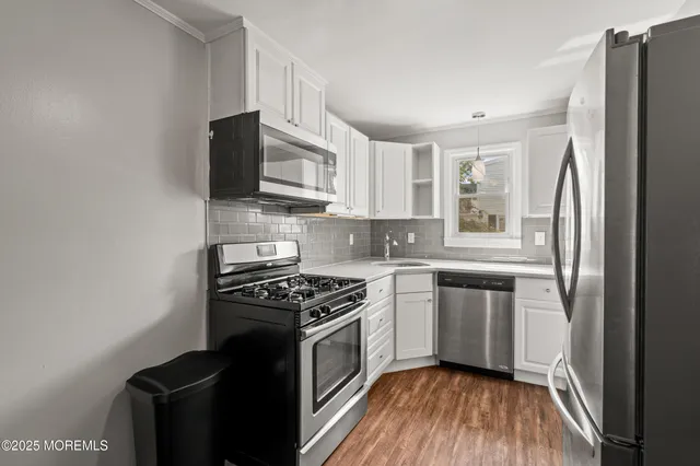 a kitchen with stainless steel appliances a refrigerator a sink a stove top oven and wooden floor