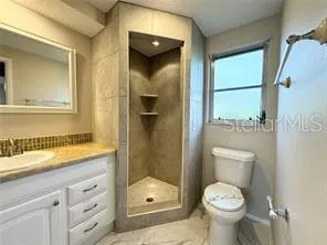 a bathroom with a granite countertop toilet a sink and shower