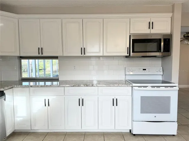 a kitchen with granite countertop white cabinets and white appliances