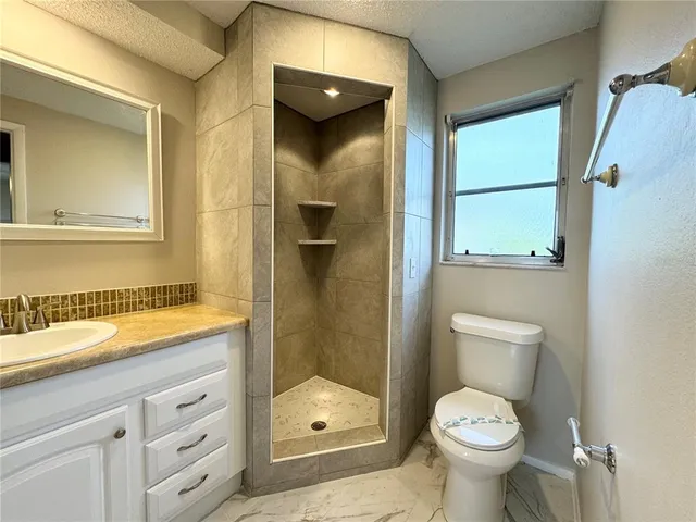 a bathroom with a granite countertop sink toilet and shower