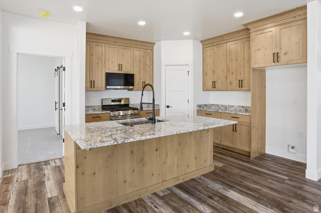 1315 West 3200 South, Unit 17 Perry, UT 84302 - Photo 14 of 58 Kitchen featuring a large island with an undermount sink and a matte black faucet, granite countertops, and light wood cabinetry with dark hardware