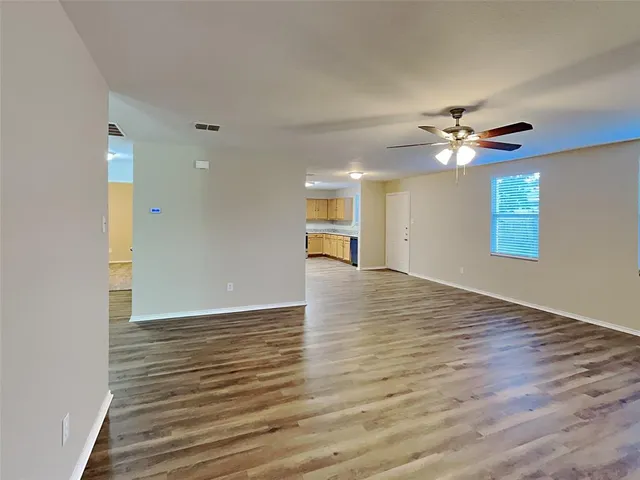 a view of an empty room with window and wooden floor