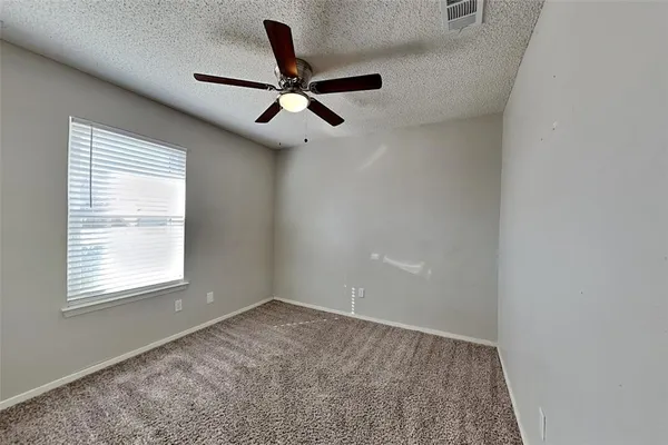 an empty room with a window and a fan