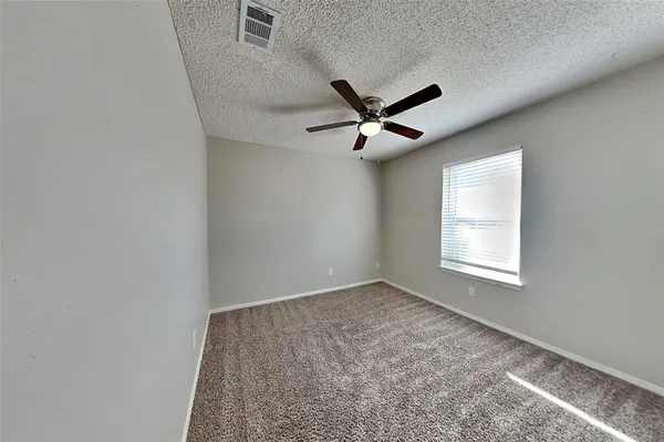 an empty room with a window and a fan