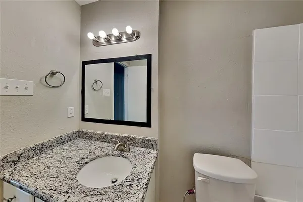 a bathroom with a granite countertop sink a toilet and a mirror