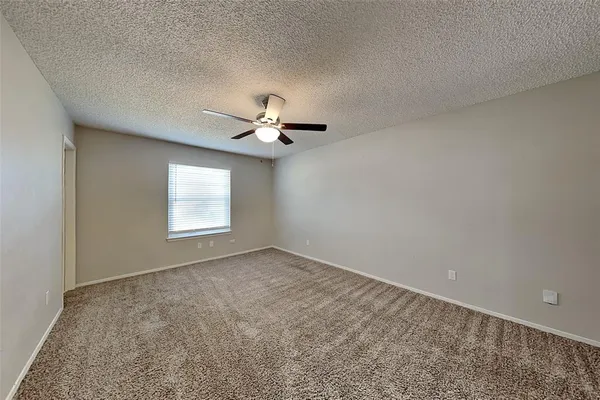 an empty room with a chandelier fan and windows