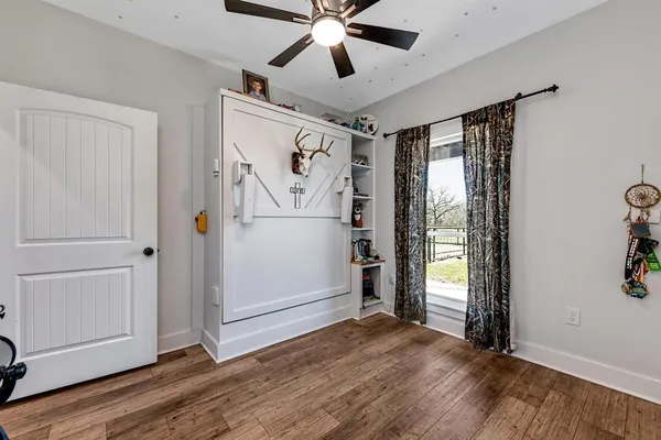 an empty room with wooden floor ceiling fan and windows
