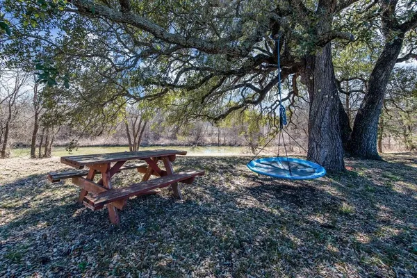 a view of a backyard with table and chairs under a large tree
