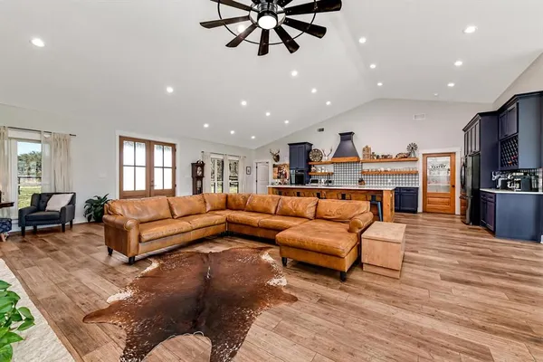a living room with furniture kitchen view and a wooden floor
