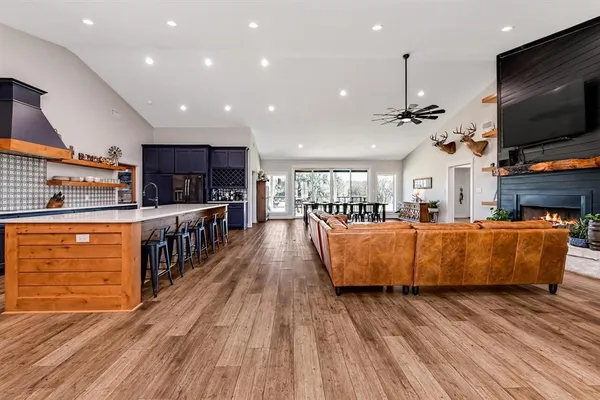 a living room with stainless steel appliances kitchen island lots of furniture and wooden floor