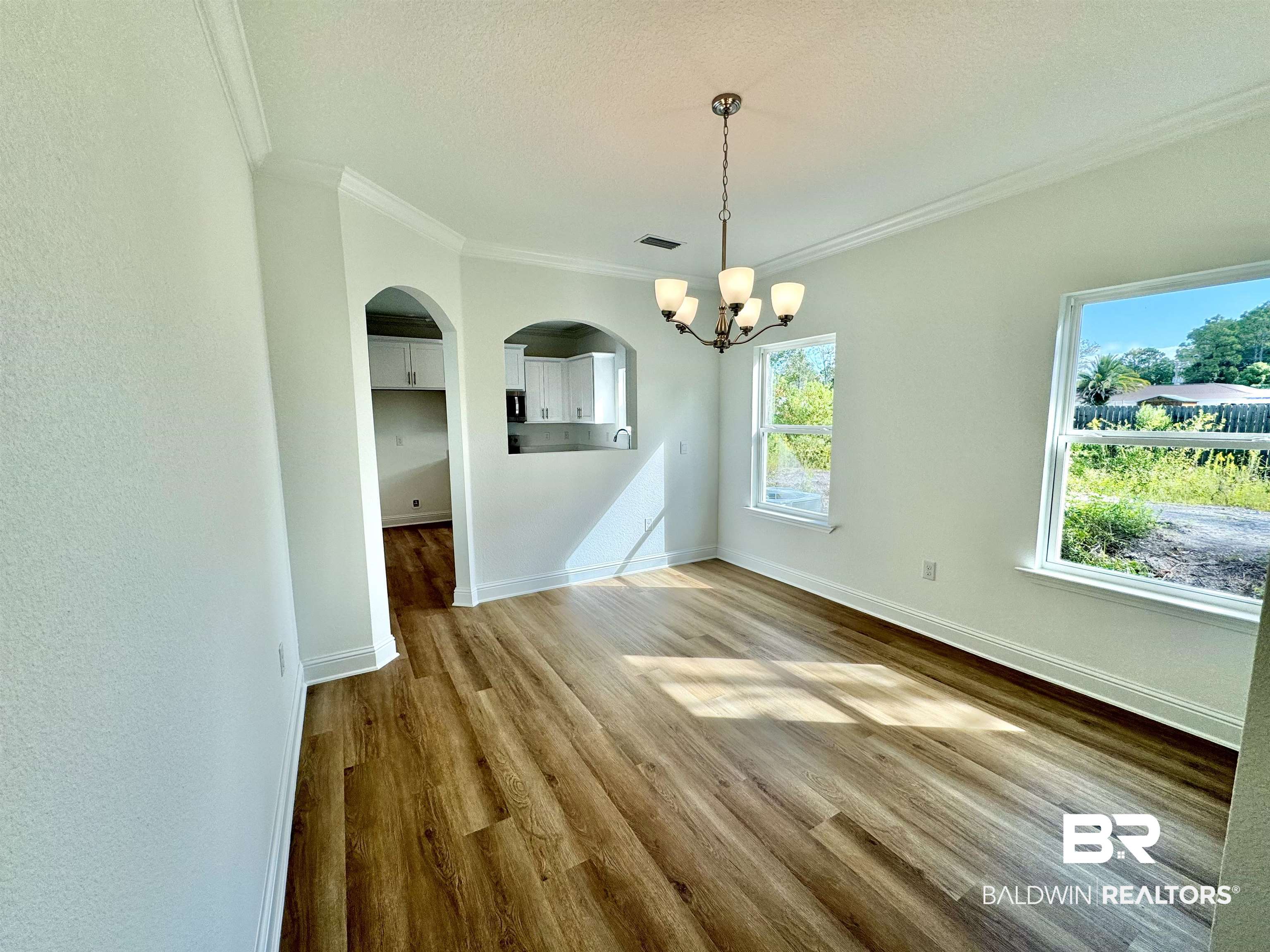 27491 Canal Road Orange Beach, AL 36561 - Photo 10 of 20 Unfurnished dining area featuring a textured ceiling, wood-type flooring, an inviting chandelier, ornamental molding, and sink