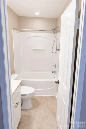 a bathroom with a granite countertop bathtub shower sink vanity and a toilet