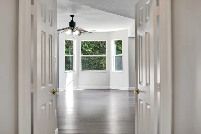 a view of an empty room with wooden floor and a window