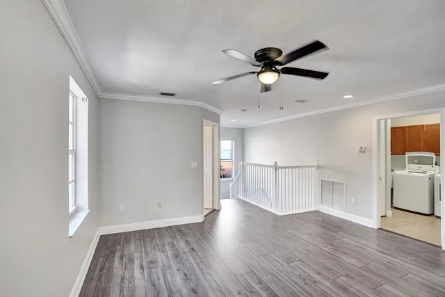 a view of empty room with wooden floor and ceiling fan