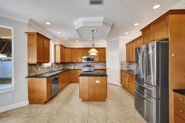 a kitchen with stainless steel appliances granite countertop a refrigerator a sink a stove top oven and a refrigerator