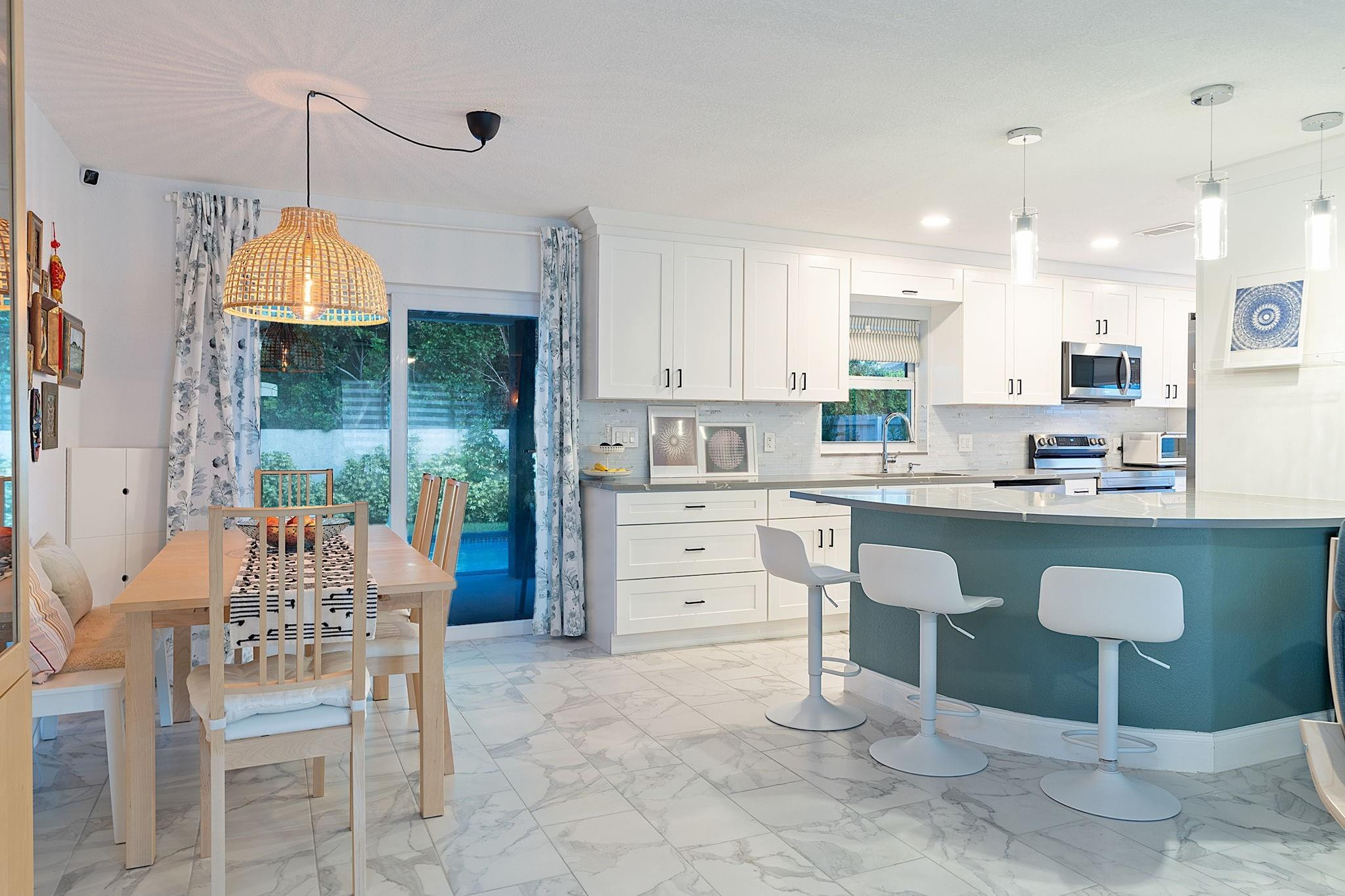 22848 Southwest 54th Way Boca Raton, FL 33433 - Photo 10 of 44 a kitchen with kitchen island granite countertop a table chairs sink and cabinets