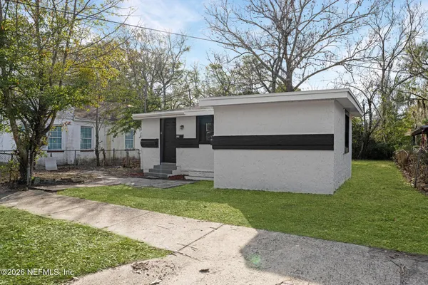 a view of a house with a yard and large tree