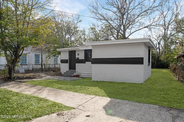 a view of a house with a yard and large tree