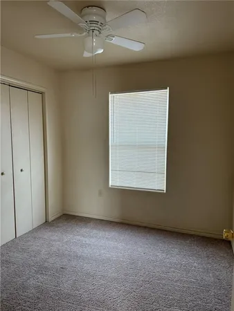 an empty room with a ceiling fan and window