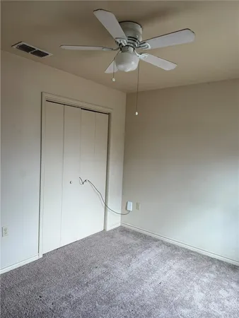 a view of an empty room and chandelier fan