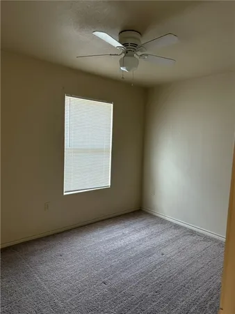 an empty room with a ceiling fan and window